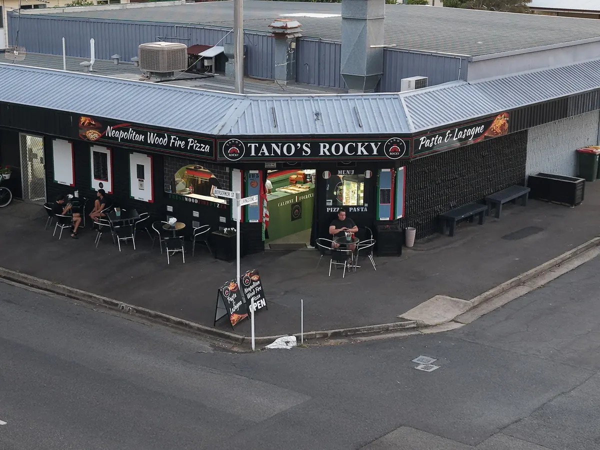 Drone photo of the Tano’s Rocky corner shopfront in daylight, with the Neapolitan Wood Fire Pizza and Pasta & Lasagne signs