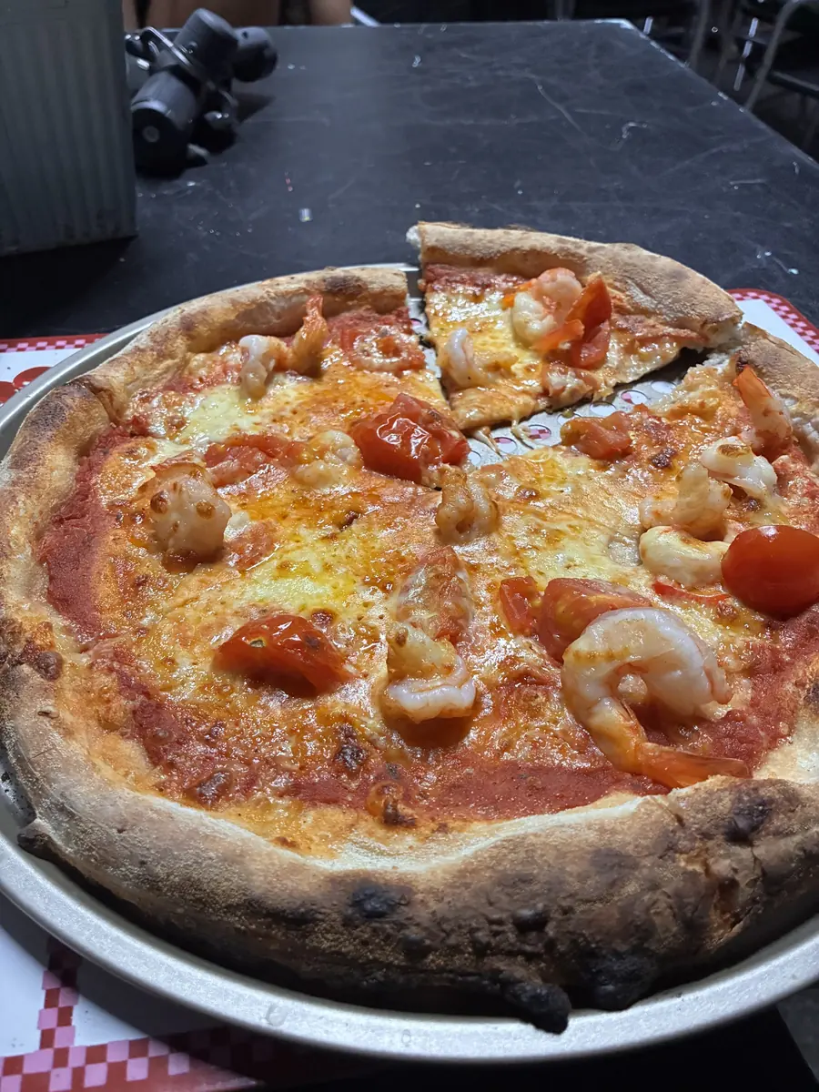Wood-fired pizza with prawns, cooked with a charred leopard-spotted crust